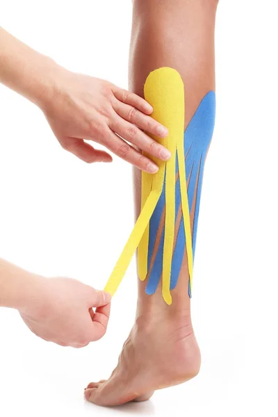 Obrázek ukazující speciální fyzioterapie pásku vložit na zraněné tele nad bílým pozadím — Stock fotografie