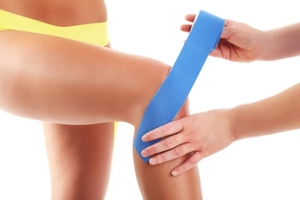 Afbeelding van speciale physio tape zetten gewonde knie op witte achtergrond — Stockfoto