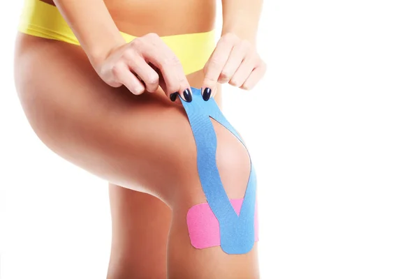 Bild mit speziellem Physiotape auf verletztem Knie vor weißem Hintergrund — Stockfoto