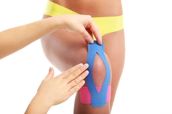 Afbeelding van speciale physio tape zetten gewonde knie op witte achtergrond — Stockfoto