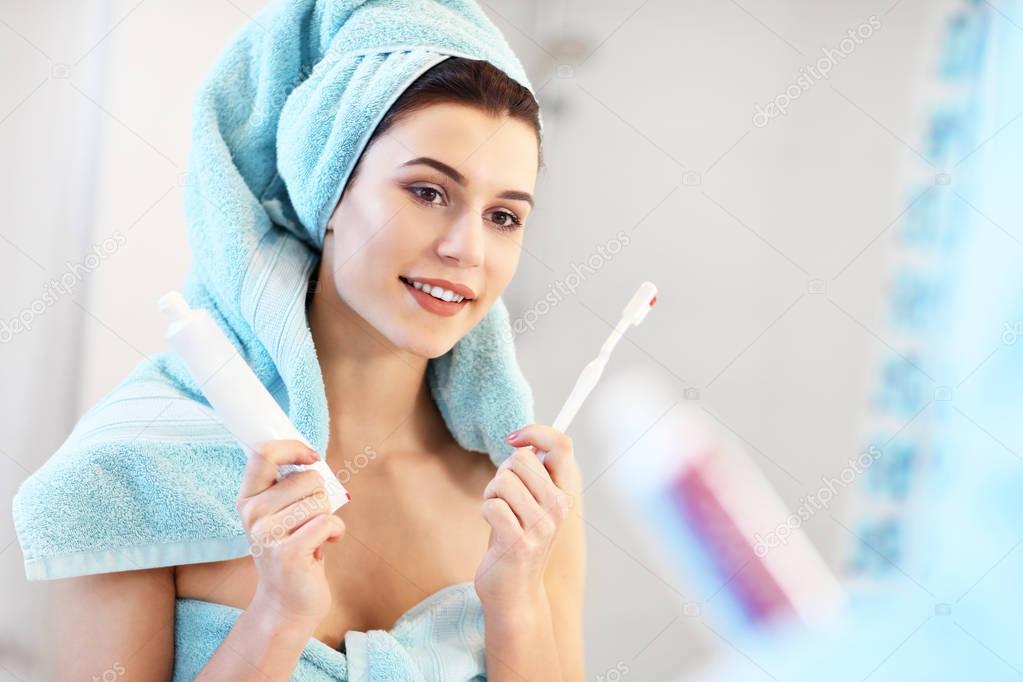 Young woman washing teeth in bathroom in the morning