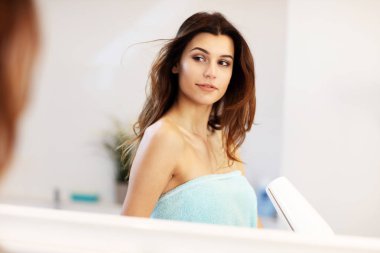 Sabah banyoda saç kurutma makinesi kullanan genç kadın