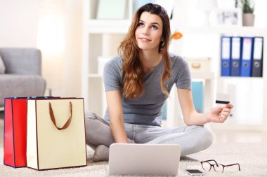 Güzel bir kadın kredi kartıyla online alışveriş yapıyor.