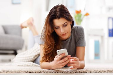 Evde telefon oturma odasında kullanan mutlu yetişkin kadın