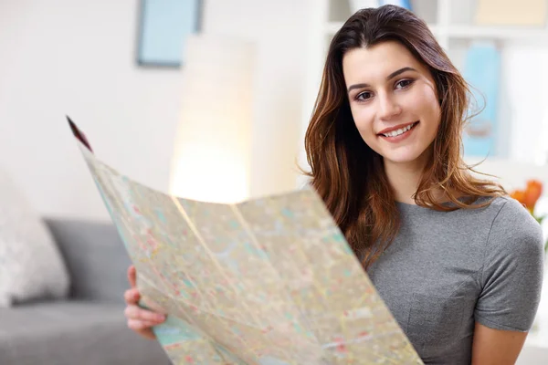 Щаслива жінка з картою вдома планує відпустку — стокове фото