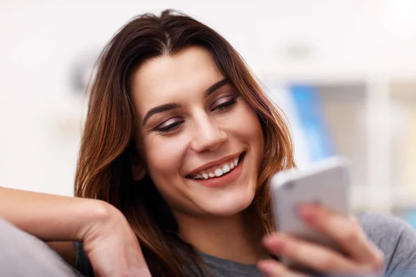 Lycklig vuxen kvinna använder telefon hemma i vardagsrummet — Stockfoto