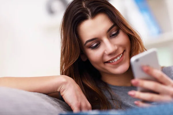 Mujer adulta feliz usando el teléfono en casa en la sala de estar —  Fotos de Stock