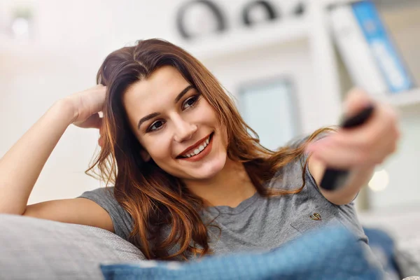 Hermosa joven mujer relajándose en casa viendo la televisión — Foto de Stock