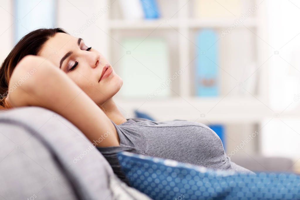 Relaxed young woman enjoying rest on comfortable sofa