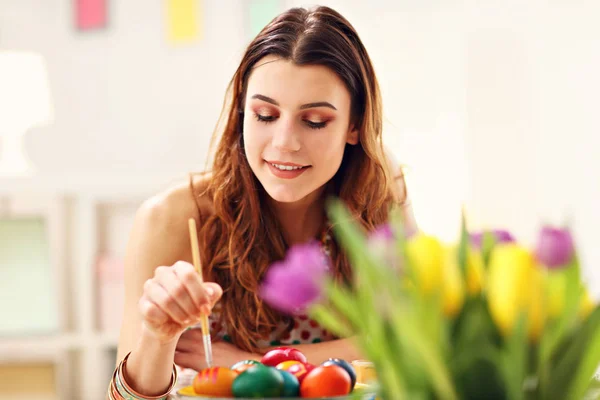 Atractiva mujer pintando huevos de Pascua en casa —  Fotos de Stock