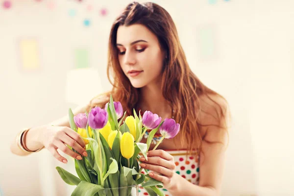 Mulher atraente organizando flores de tulipas em vaso — Fotografia de Stock