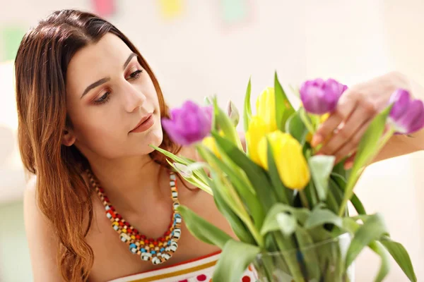 Attractive woman arranging tulips flowers in vase — Stock Photo, Image