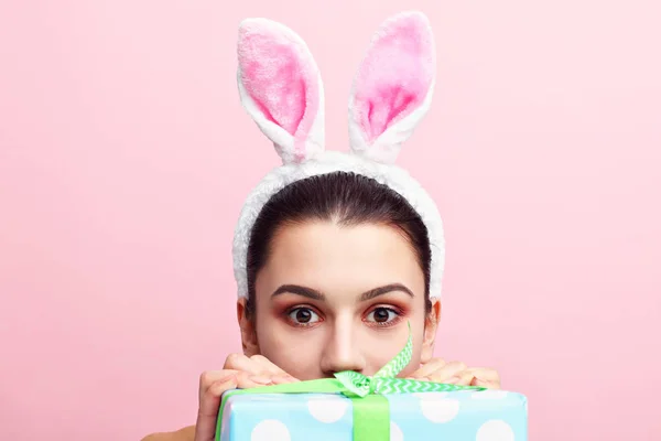 Glad ung kvinna bär bunny öron och håller nuvarande — Stockfoto