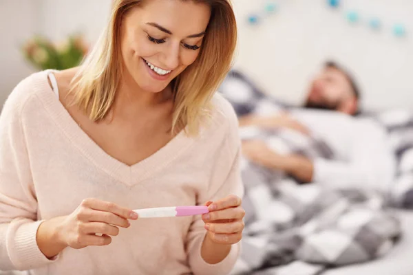 Casal feliz com teste de gravidez no quarto — Fotografia de Stock