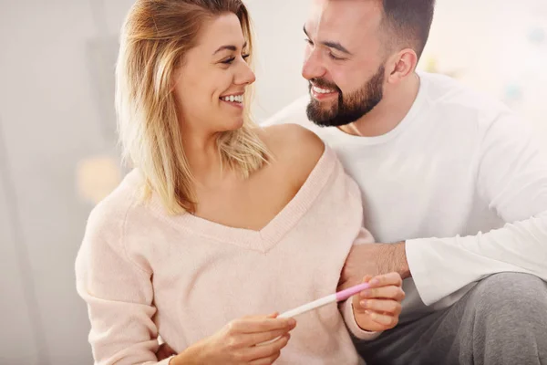 Casal feliz com teste de gravidez no quarto — Fotografia de Stock