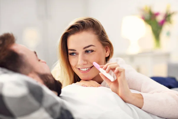 Lyckligt par med graviditetstest i sovrum — Stockfoto