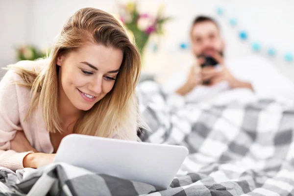 Casal adulto com computador portátil na cama — Fotografia de Stock