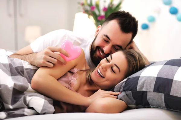 Adulto pareja atractiva en la cama con presente —  Fotos de Stock