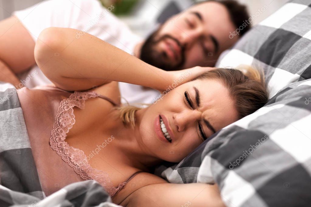 Adult couple suffering from snoring problem in bed
