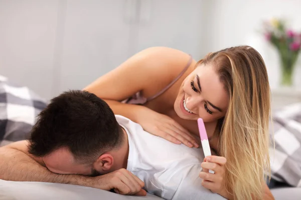 Adulto casal surpreso com teste de gravidez no quarto — Fotografia de Stock