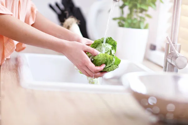 Giovane donna che lava lattuga in cucina moderna — Foto Stock