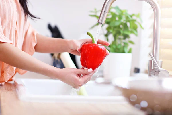 Jonge vrouw wassen rode paprika in moderne keuken — Stockfoto