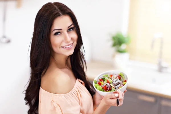 Mulher feliz preparando salada na cozinha moderna — Fotografia de Stock