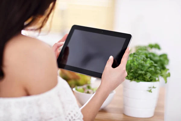 Glückliche Frau bereitet Salat in moderner Küche zu und hält Tablette in der Hand — Stockfoto