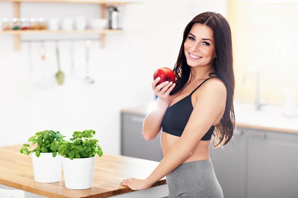 Modern mutfak içinde elma ile uygun gülümseyen genç kadın — Stok fotoğraf