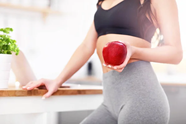 Ajuste mujer joven con manzana en la cocina moderna —  Fotos de Stock