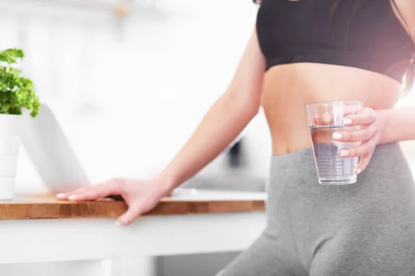 Ajuste mujer joven con vaso de agua en la cocina moderna —  Fotos de Stock