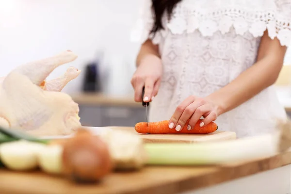 Jonge vrouw probeert te bereiden kippensoep in keuken — Stockfoto