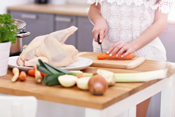 Jonge vrouw probeert te bereiden kippensoep in keuken — Stockfoto