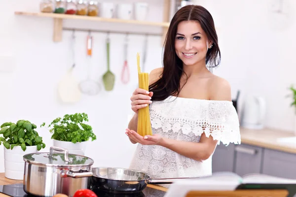Young woman trying to prepare pasta in kitchen — Stock Photo, Image