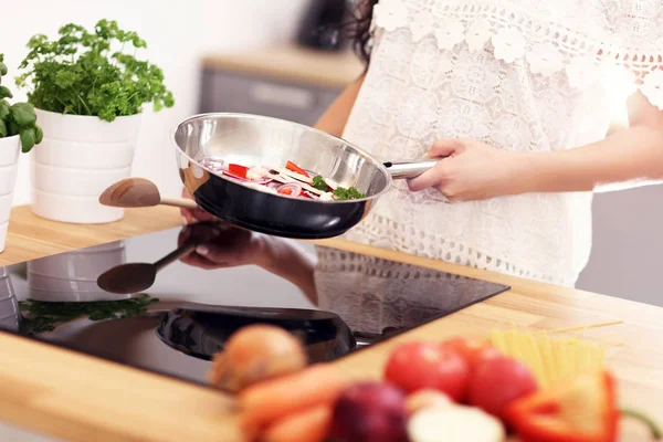 Junge Frau bereitet in Küche gebratenes Gemüse zu — Stockfoto