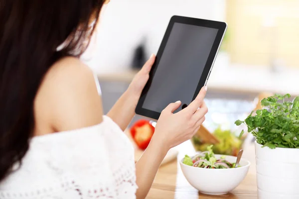 Donna felice preparare insalata in cucina moderna e tablet tenuta — Foto Stock