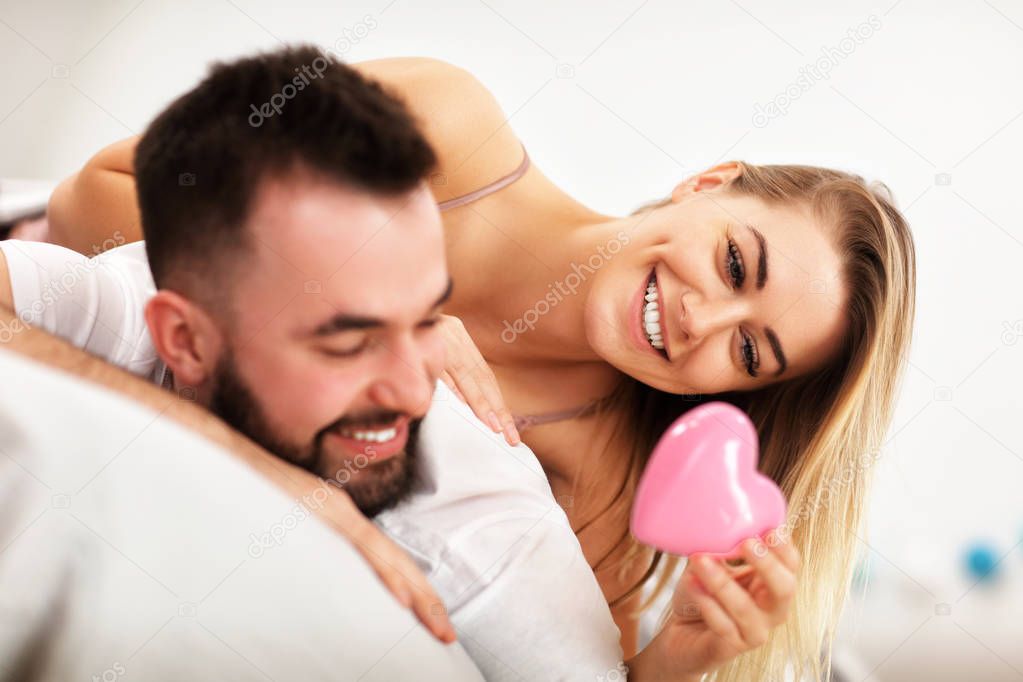Adult attractive couple in bed with present
