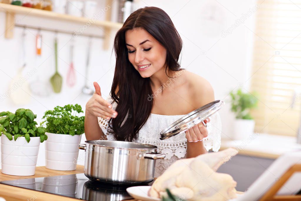 Young woman trying to prepare chicken soup in kitchen