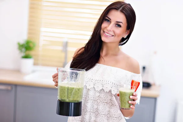 Fit lächelnde junge Frau bereitet gesunden Smoothie in moderner Küche zu — Stockfoto