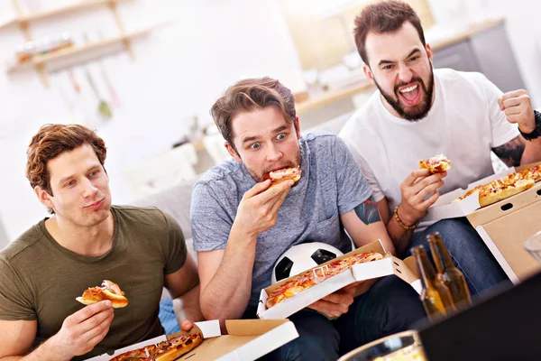 Happy male friends eating pizza and watching tv — Stock Photo, Image