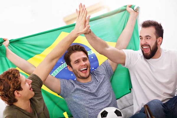 Happy male friends cheering and watching sports on tv — Stock Photo, Image