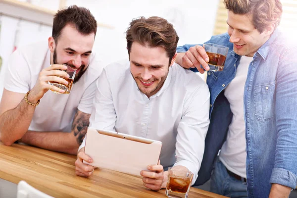 Vrolijke vrienden met plezier met smartphone en het thuis drinken — Stockfoto