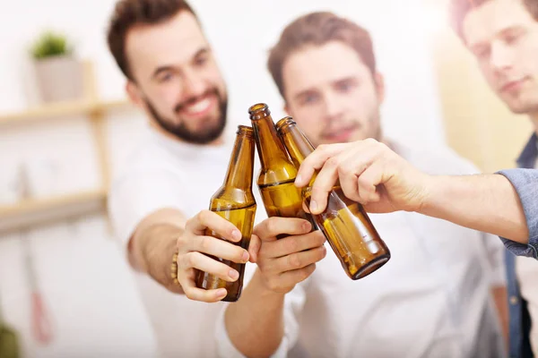 Amigos alegres que se divierten con el teléfono inteligente y beber en casa — Foto de Stock