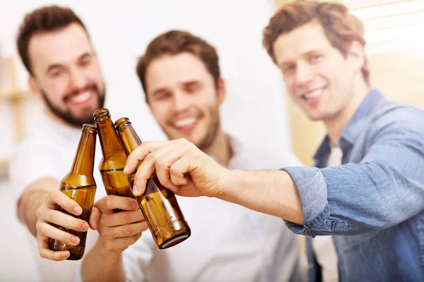 Amigos alegres que se divierten con el teléfono inteligente y beber en casa — Foto de Stock