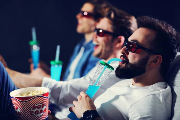 Gruppo di amici felici seduti nel cinema guardare film e mangiare popcorn — Foto Stock