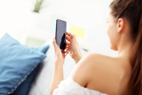 Gelukkige vrouw thuis ontspannen met smartphone — Stockfoto