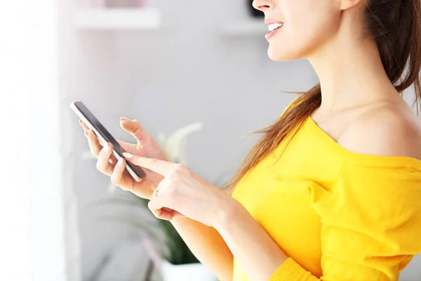 Mulher feliz relaxando em casa com smartphone — Fotografia de Stock