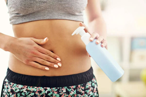 Woman using body lotion on her belly — Stock Photo, Image