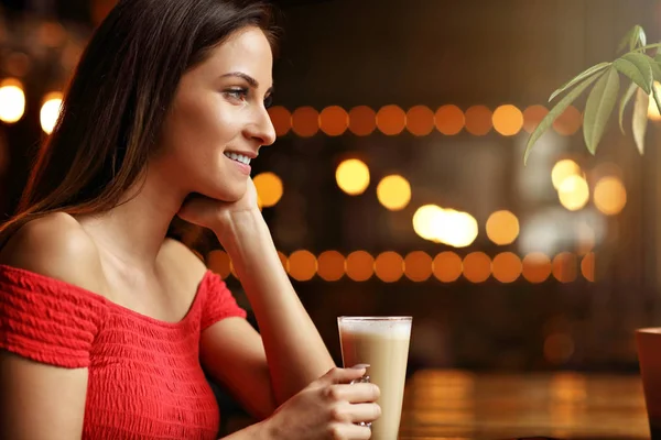 Ung kvinne som drikker kaffe på en kafe – stockfoto
