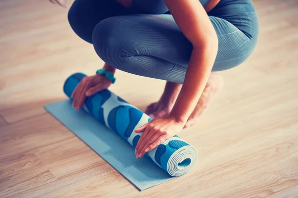 Young woman rolling yoga mat at home — Stock Photo, Image